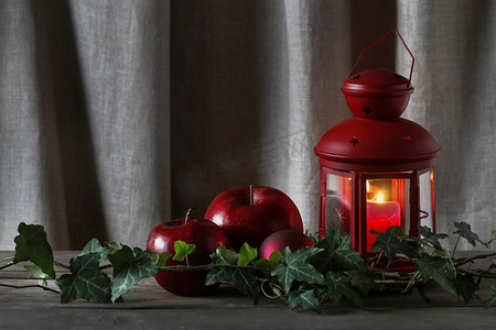 candle摄影照片_Christmas decoration with red lantern, candle, apples and ivy le