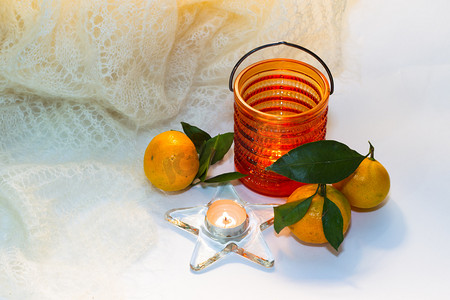 黄色页摄影照片_静物与橘子、 羽毛披肩和糖果中的蜡烛