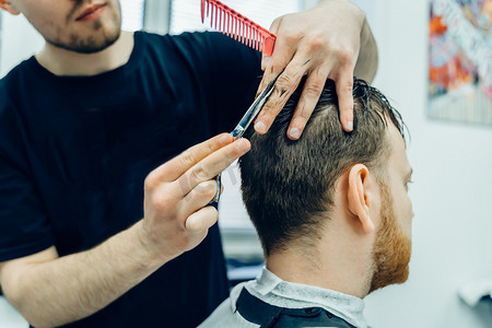 樱花纹身摄影照片_纹身理发师用剪刀剪掉客户的头发。靠近点有魅力的男性正在理发店理发.近景.