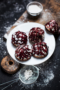 小甜点背景摄影照片_带有不同填料的小甜点, 洒上浆果馅料, 在深色背景的木板上洒上糖粉在白色的盘子上。