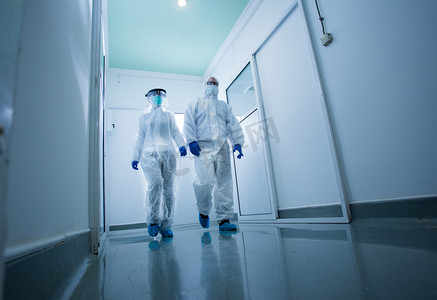 穿着防护服的研究人员穿过实验室大厅。病毒和疾病安全概念
