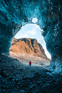 发现了摄影照片_独木舟女探险旅行者在靠近Jokulsarlon冰川湖的Vatnajokull冰川发现了冰岛的冰洞。被遗弃的冰岛的旅游业。户外生活和探索 