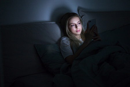 沉迷手机摄影照片_社交网络成瘾，游牧民族恐惧症，失眠，睡眠障碍的概念。女人沉迷于24 / 7连接互联网的智能手机，深夜躺在床上用智能手机.  