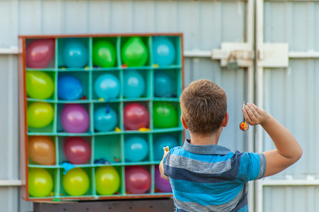 男孩在后院玩气球飞镖 - 一个盒子或设置与合作