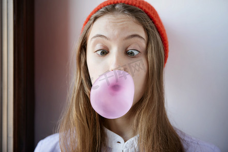 美丽和震惊或惊讶的年轻学生女孩吹泡沫从嚼口香糖.