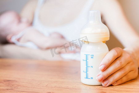 Mother holding a baby bottle with breast milk with scale
