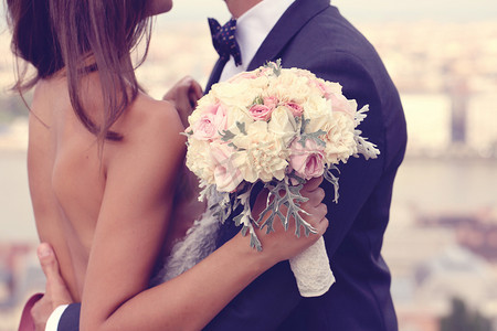 详细的新娘和新郎拥抱。新娘抱着美丽的婚礼花束