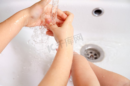 学前教育摄影照片_儿童在自来水下的白色水槽洗手