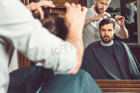 理发店理发摄影照片_年轻英俊的理发师在理发店理发的有魅力的男人
