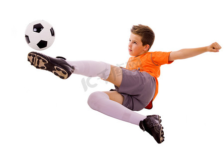 跨越式摄影照片_年轻的男孩做飞脚，孤立在白色的足球球