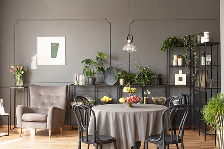 桌上有黑色的椅子, 里面有灰色阁楼的水果, 旁边有扶手椅和鲜花。真实照片