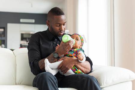 年轻的非洲裔美国父亲给她的宝贝女儿在牛奶