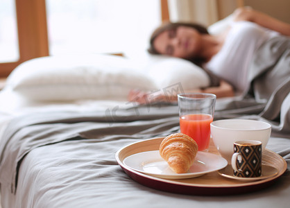 美容床摄影照片_与咖啡和牛角面包吧，年轻漂亮的女人床上早餐