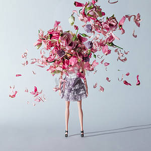 玫瑰创意设计摄影照片_带粉红色和紫色花朵的女孩娃娃。创意简约时尚