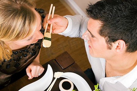 晚餐用寿司喂对方的情侣，浪漫的环境，想必这是一次提前约会；浅浅地关注眼睛