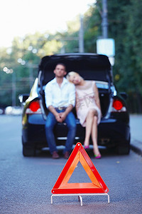 年轻夫妇在一辆汽车与红色三角形在前景