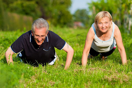 穿着慢跑装备的成年或老年夫妇在户外做运动和身体锻炼，俯卧撑