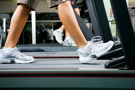 两个人(男/女)在健身房的跑步机上锻炼