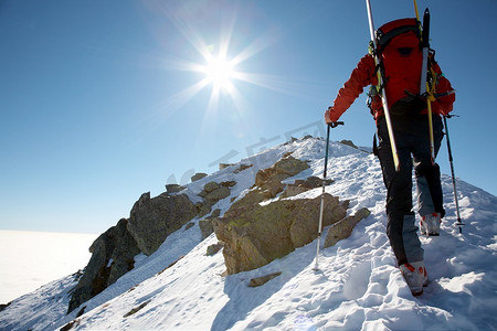 防范气候摄影照片_男子滑雪攀登者攀登积雪的山脊；水平体格。意大利阿尔卑斯山。