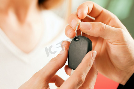 经销商摄影照片_一名女子在汽车经销商购买一辆汽车，销售代表给了她钥匙，微距镜头聚焦在手和钥匙上