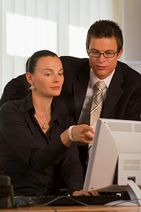 一名男性和女性上班族一起看着电脑显示器