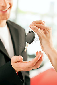 男子在汽车经销商购买汽车，女销售代表给他的关键，宏观拍摄重点在手和关键