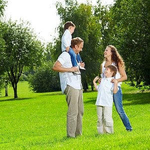 笑着的一家人带着两个儿子在夏日花园散步