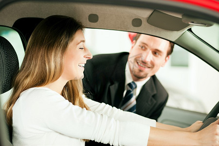 女人买一辆车在经销商坐在她的新车，销售员在后台跟她说话