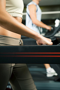 两个人(男/女)在健身房的跑步机上锻炼
