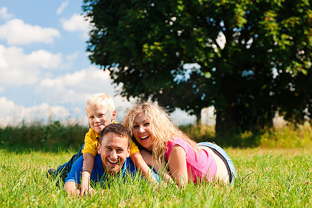 阳光明媚的夏日，年轻的一家人在草地上嬉戏嬉戏