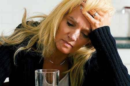非常沮丧，悲伤或脾气暴躁的女人用一杯水头痛（大概是水里有止痛药）