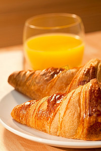 金色牛摄影照片_健康的欧式早餐，牛角面包糕点，橙汁，金色的清晨阳光照亮。