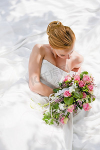 新娘坐在那里，手里拿着一束花