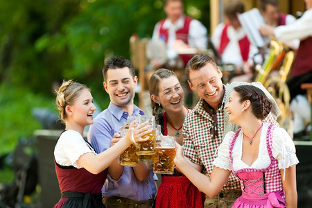 在德国巴伐利亚州的啤酒花园-Tracht的朋友，Dirndl和Lederhosen和Dirndl站在乐队前面
