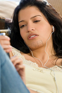 一位年轻漂亮的西班牙裔妇女躺在地上，在她的MP3播放器上享受着音乐