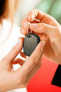 一名女子在汽车经销商购买一辆汽车，销售代表给了她钥匙，微距镜头聚焦在手和钥匙上