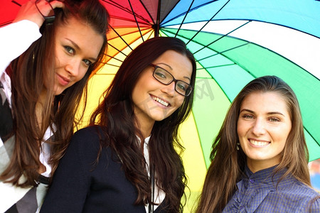 快乐微笑的女朋友们留在五颜六色的伞下