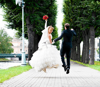 手拉手摄影照片_新郎新娘手拉手在城市公园路上奔跑