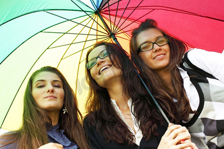 女朋友们摄影照片_快乐微笑的女朋友们留在五颜六色的伞下