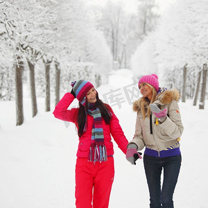 背景是两个女人走过冬日小巷里的雪树