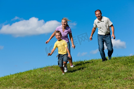 公路奔跑摄影照片_在一个美丽的夏日，快乐的一家人在户外的一条土路上奔跑--他们试图抓住对方