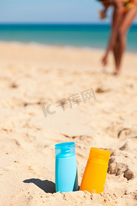 在海滩的沙滩上放两瓶防晒霜-很多保护措施