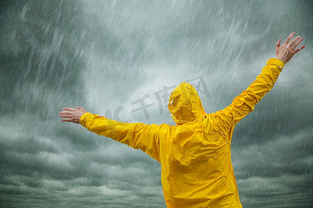 穿着黄色外套的男子享受着雨，选择性地聚焦