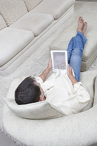 男人双脚朝上坐着看电子书