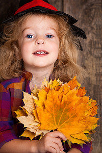 快乐的孩子拿着秋叶。万圣节概念