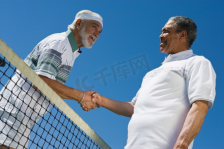 两名男子在网球网上握手