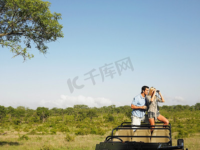 夫妇在safari站在吉普车女人看通过望远镜