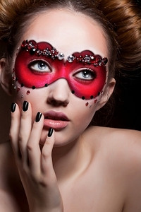 画了一张脸。戴着红色狂欢节面具的漂亮女孩。化妆舞会