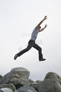 一名男子举起手臂跳过岩石