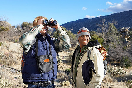 两名年轻人在山上徒步旅行时使用双筒望远镜